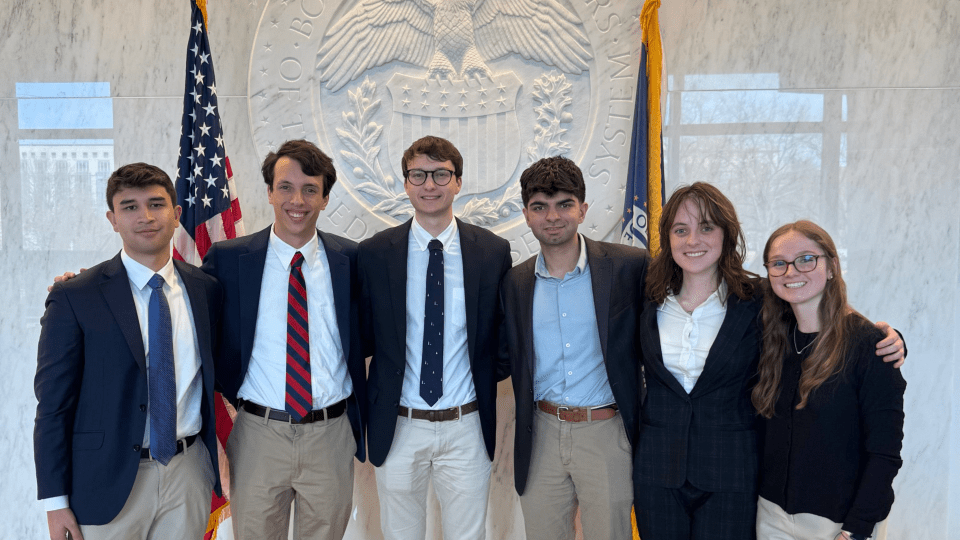 a group of six young people standing in front of the federal reserve building