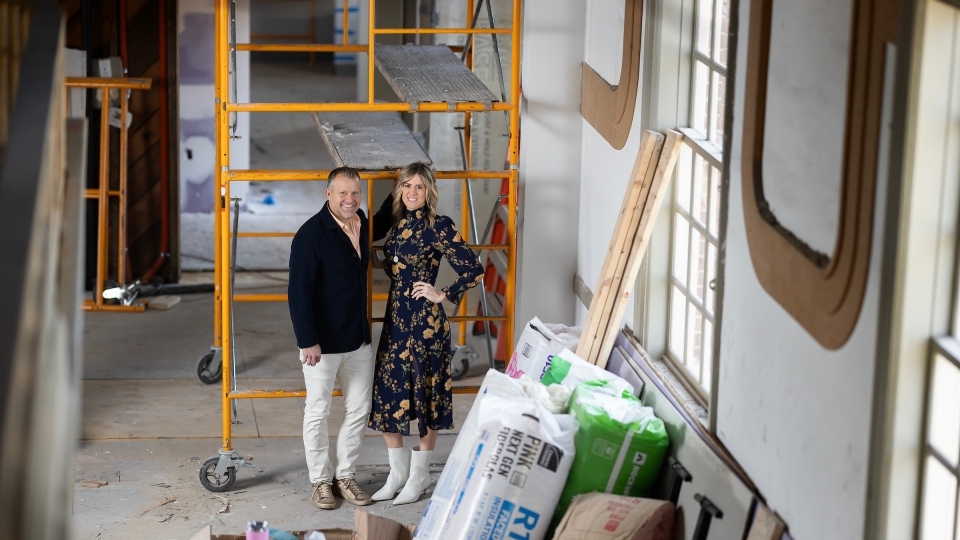 a young white couple stand together in a church under renovation