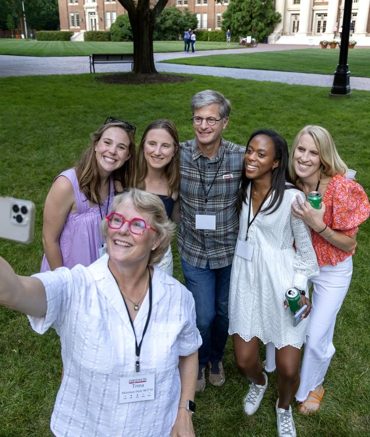 a group of alums pose to take a selfie together outside