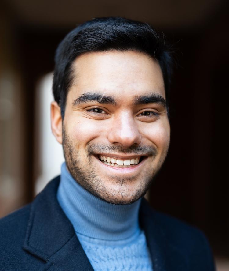 a young man wearing a blue turtleneck and blazer