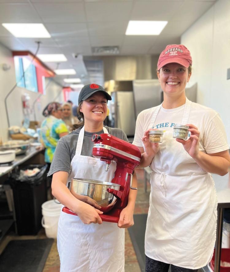 Kayla Sonneby and Kelley Callaway of Butter from the Block in the kitchen. One woman is holding a stand mixer and the other is holding jars of butter