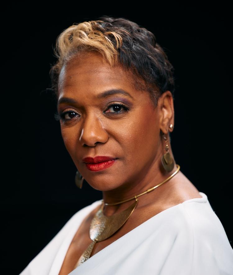 an older Black woman with short hair wearing a white blouse
