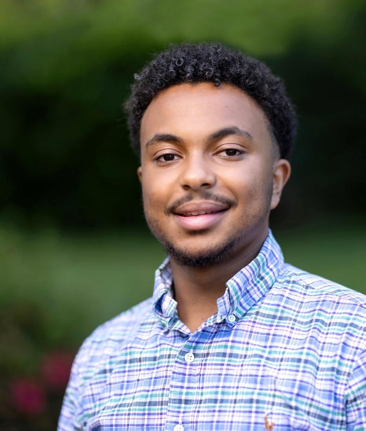 a young African man wearing a plaid shirt