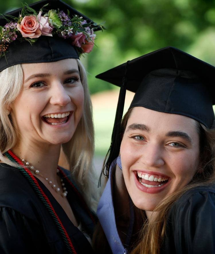 two young women with graduation caps smiling