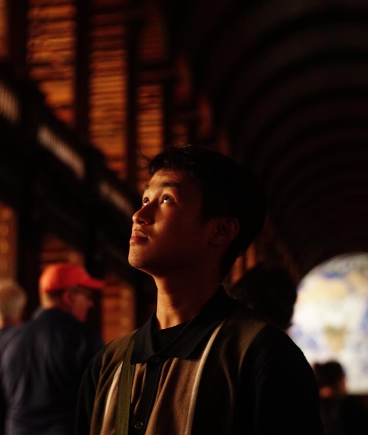 a young Vietnamese man looks up at ornate ceiling