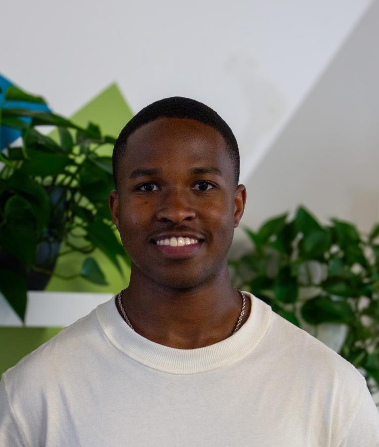 a young Black man smiling wearing a white shirt