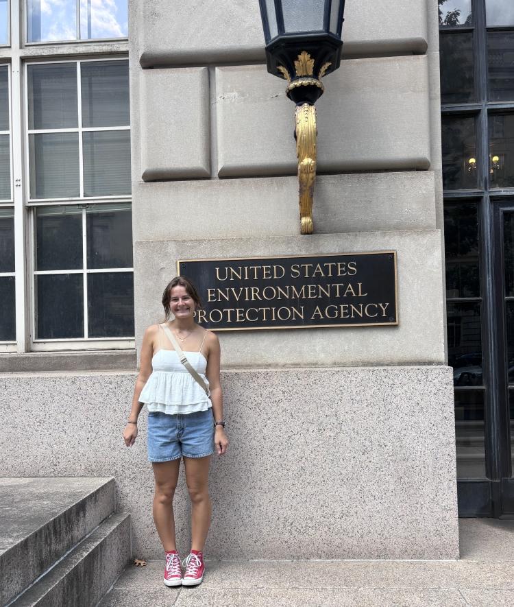 a young white woman stands in front of "US EPA" sign