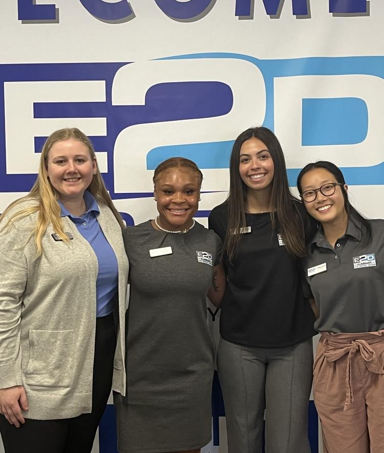 a group of young women standing in front of a wall that reads "E2D"