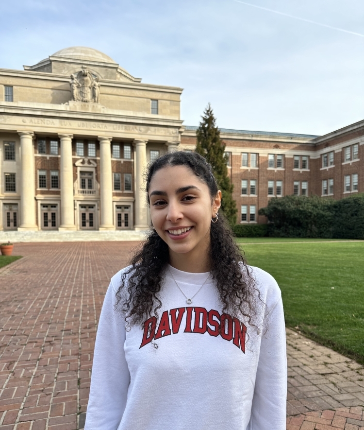 a young woman wearing a Davidson sweatshirt in front of an academic building