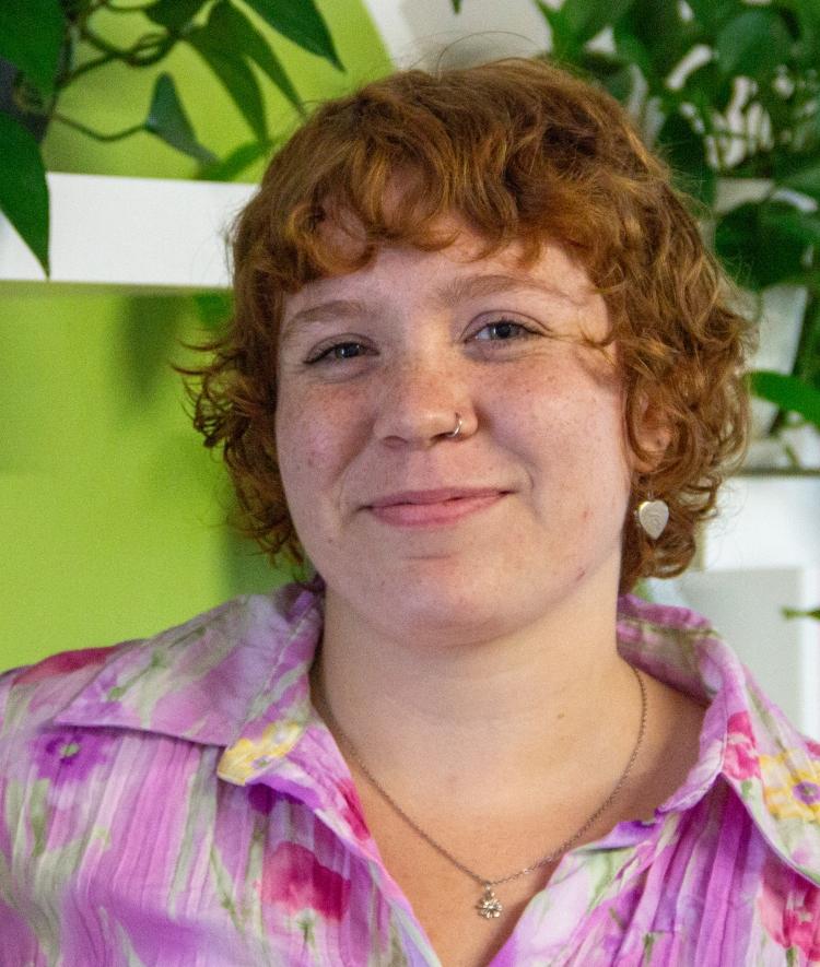 a young white woman with red hair wearing a pink top and smiling