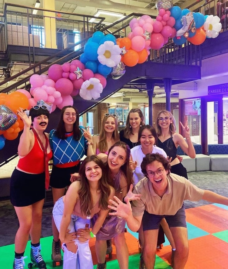 a group of students smiling together in front of a balloon arch