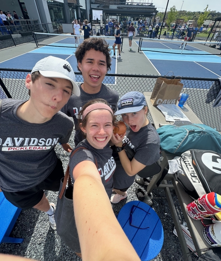 a group of students take a selfie on a pickleball court