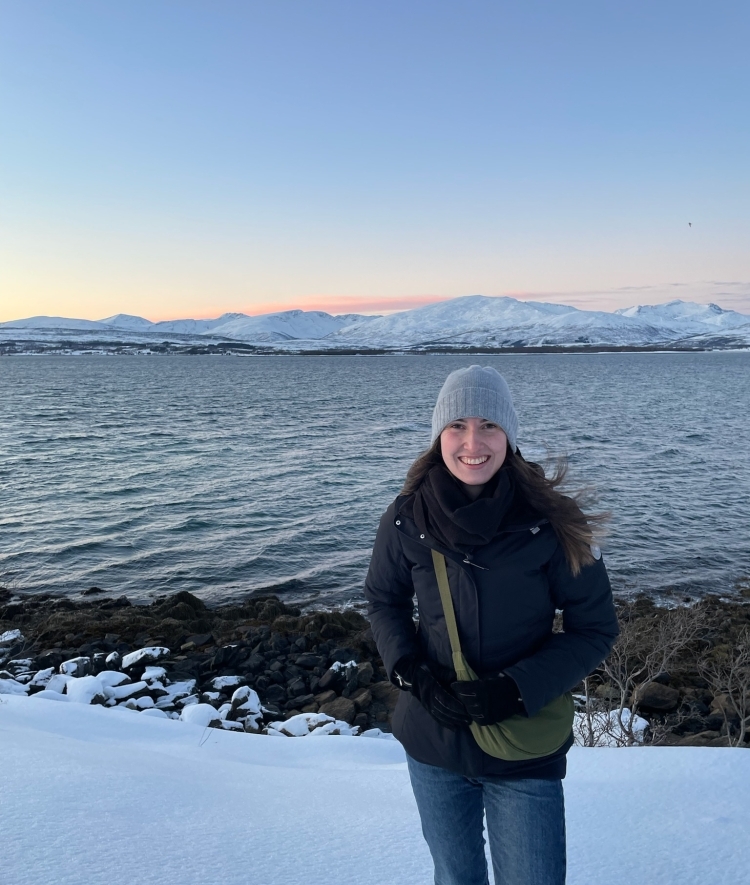 a young woman stands in front of a snowy ocean scene