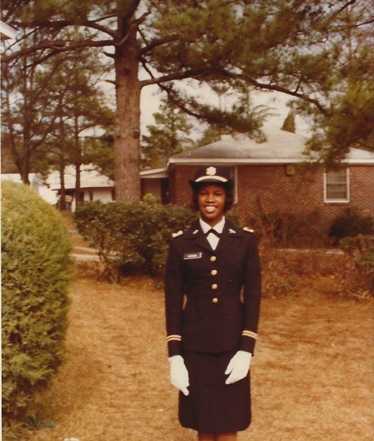 a young Black woman in military uniform standing outside