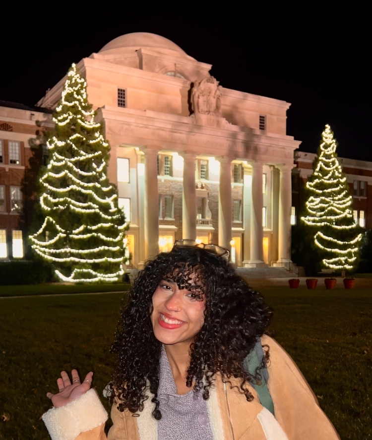 Student outside of Chambers Building with holiday lights