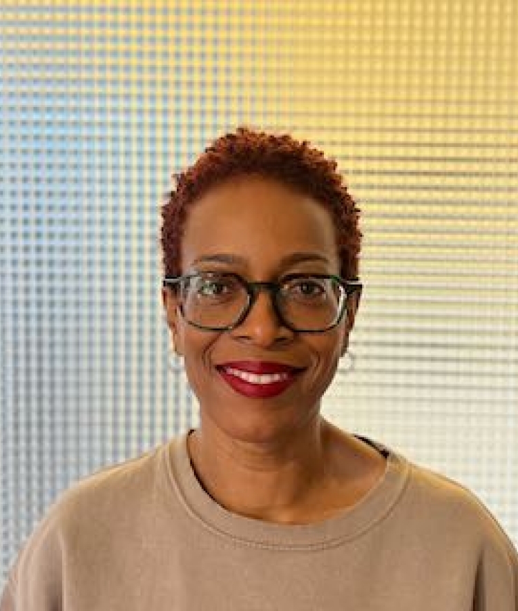 a Black woman wearing glasses with red hair smiling