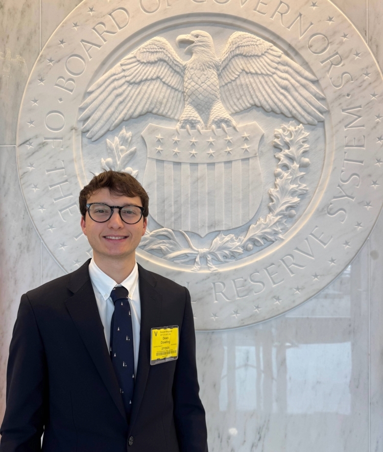 a young white man wearing a suit and tie standing in front of a government building