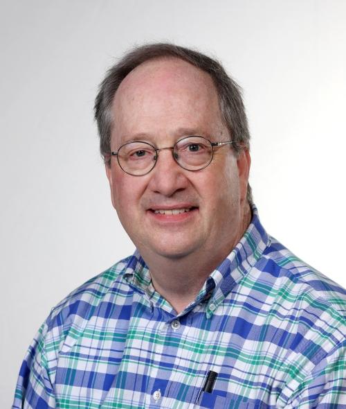 a middle aged white man wearing a plaid collared shirt