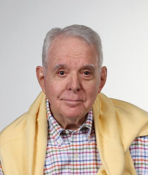 an older white man wearing a plaid shirt with a yellow sweater