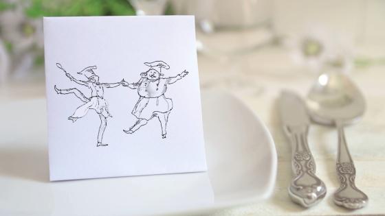 a fancy table set with a notecard of two dancing chefs on the plate