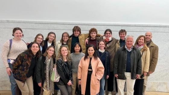 a group of students and a few adults stand together in an art gallery