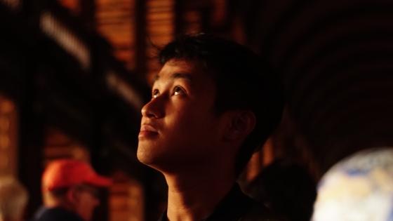 a young Vietnamese man looks up at ornate ceiling