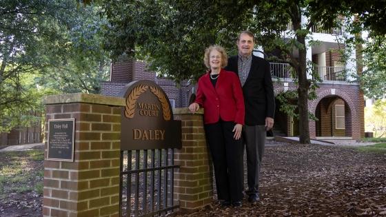 an older couple standing next to a gate