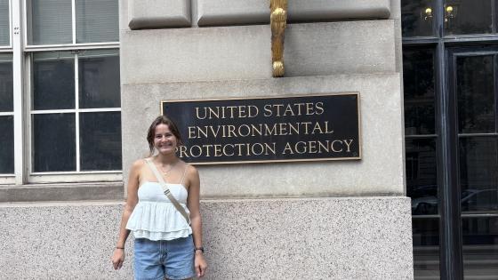 a young white woman stands in front of "US EPA" sign