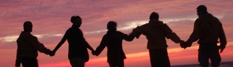 students on a beach, at sunset, holding hands 