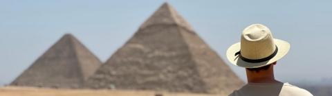 a young man stands in front of the Egyptian pyramids