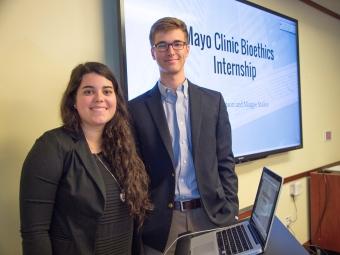 Two students stand near a screen that reads Mayo Clinic Bioethics Internship