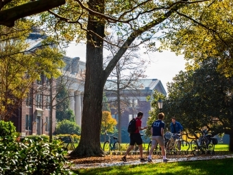 Students walk to class surrounded by trees and brick paths