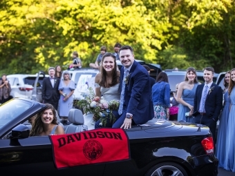 Caroline Bell '17 in car with husband and Davidson flag hanging out 