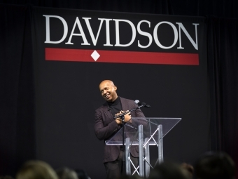 Bryan Stevenson at Belk Arena Smiling at Podium with Davidson Logo Backdrop