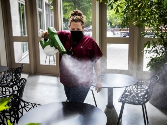 Physical Plant Worker Disinfects Table with Disinfecting Sprayer