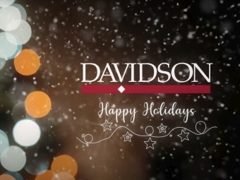 Davidson Logo and words "Happy Holidays" above a photo of some holiday lights and snow