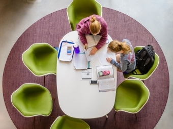 Students in Wall Studying with Textbooks and Calculators on Green Chairs