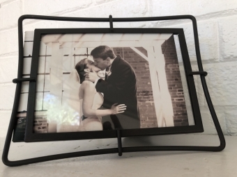 A picture frame of Andrea and David sharing a kiss in their wedding clothes 