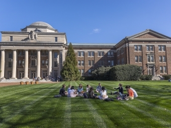 students sitting in circle outside on grass field outside Chambers building