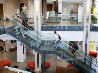 Students walk up stairs while others study in the background