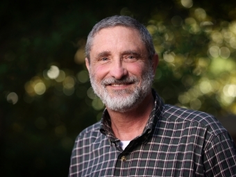 a white man smiles and wears a flannel shirt