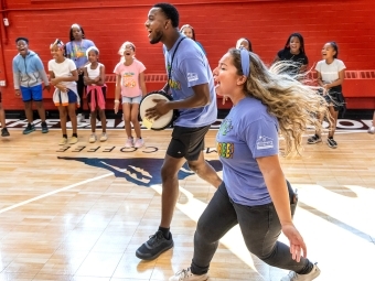 Students cheering while kids are in the background in a gym