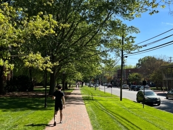 a student walks a brick sidewalk along a main street with blue skies in the background