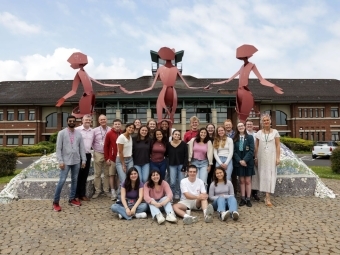 a group of students standing in front of a brick building school with large statues