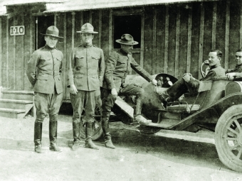 a group of soldiers in World War I uniforms stand around a car