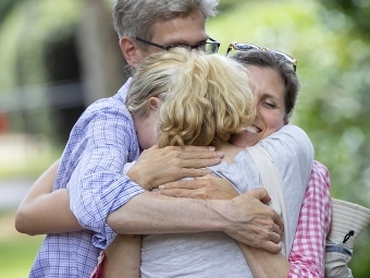 two parents hug their daughter 