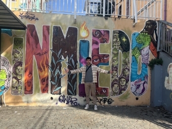 a young white man stands in front of a wall that reads " sin miedo"