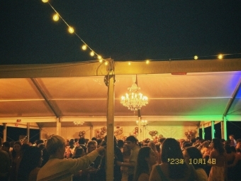 a tent covered in string lights at night and young people dancing underneath it