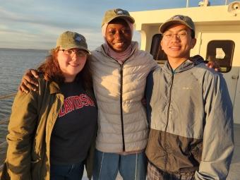 a group of three young people smiling together on a boat