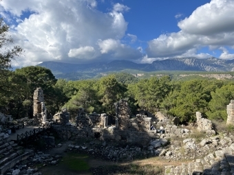 an ancient amphitheater with mountains and blue skies in the background